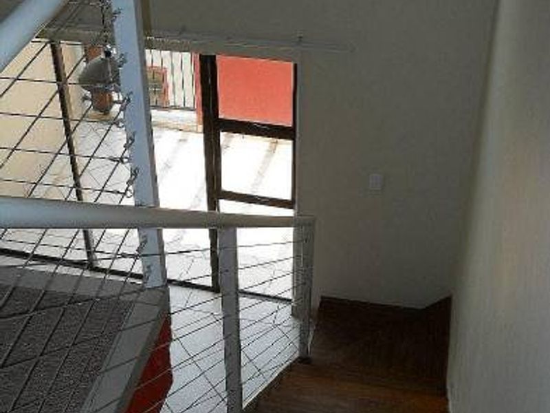 A view looking down a wooden staircase featuring a modern metal and wire cable balustrade, leading towards a sliding glass door.