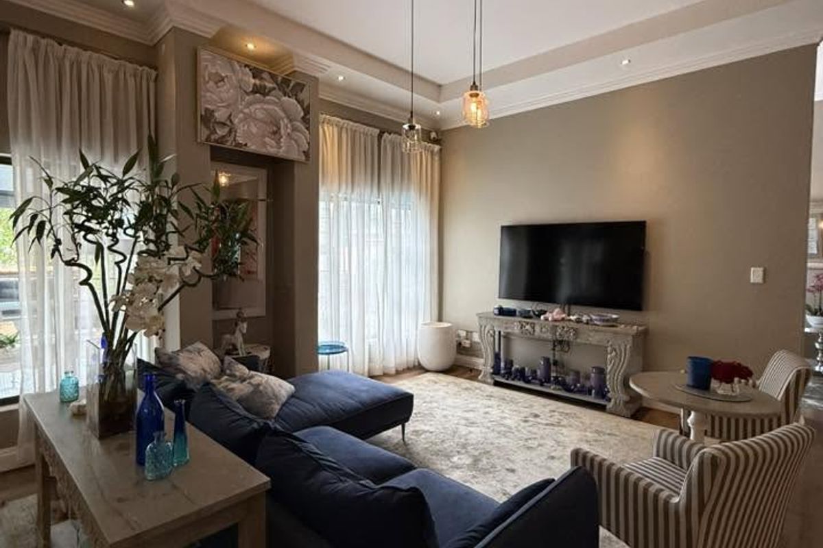A comfortable living room featuring recessed ceiling lighting, crown molding, and large windows with sheer curtains, creating a bright and inviting atmosphere.