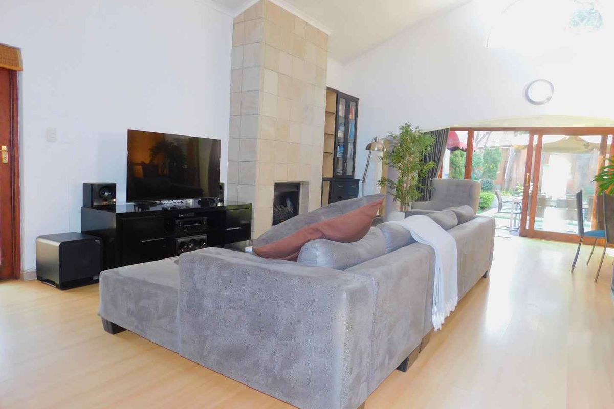 Spacious living room featuring a stone-clad fireplace, high vaulted ceilings, and large sliding doors providing seamless access to the outdoor patio area.