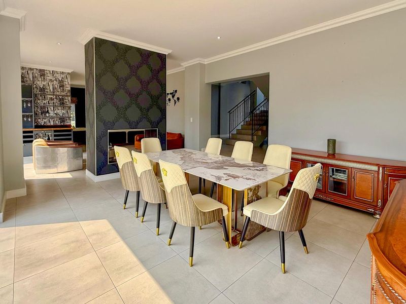 Spacious dining area featuring tiled flooring, a central fireplace with decorative feature wall, and an open-plan layout leading to the staircase.