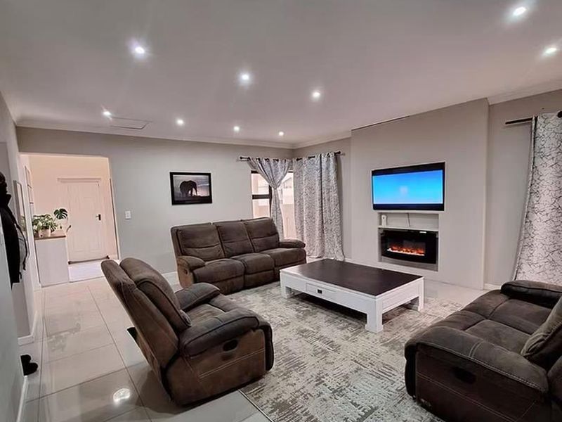 Spacious living room featuring modern tiled flooring, recessed downlighting, and a built-in electric fireplace with a dedicated television niche.