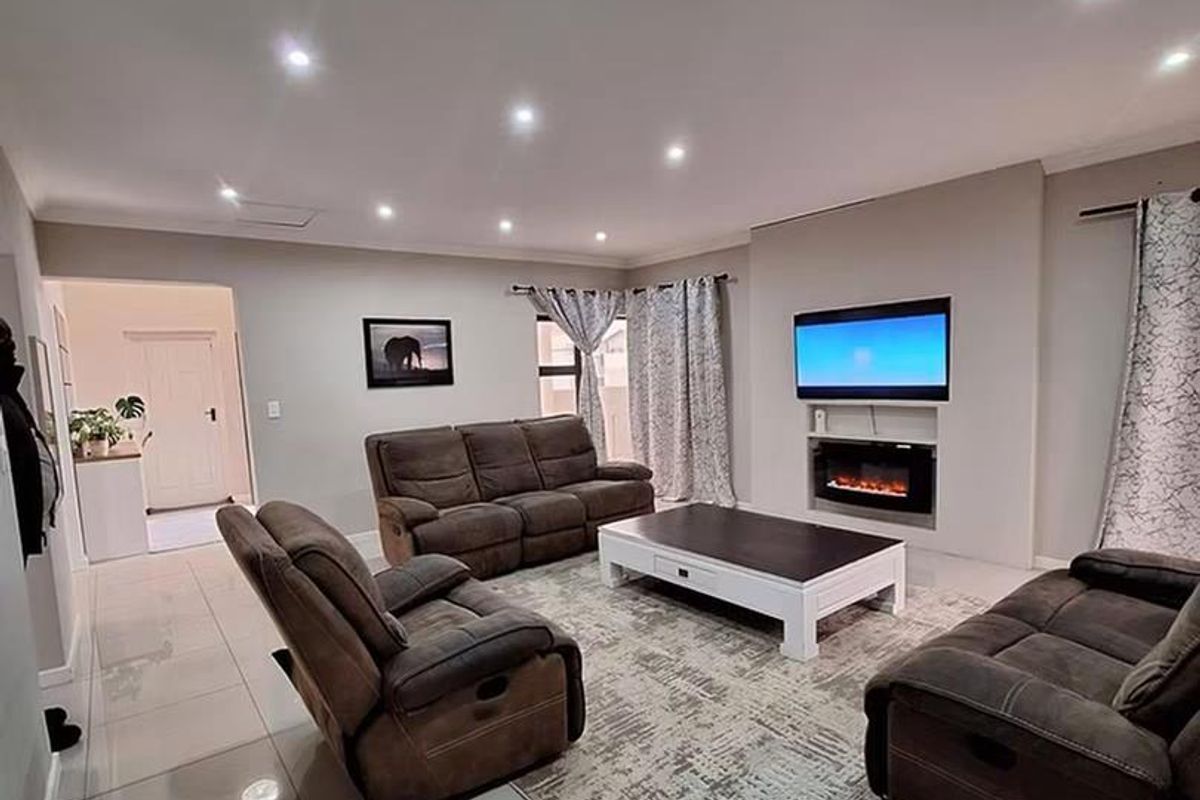 Spacious living room featuring modern tiled flooring, recessed downlighting, and a built-in electric fireplace with a dedicated television niche.