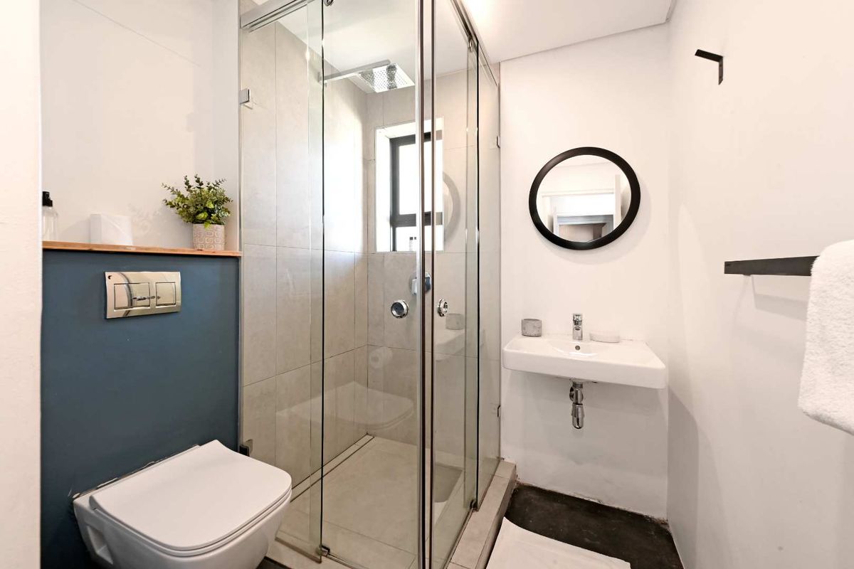 Modern bathroom featuring a glass-enclosed shower, wall-hung toilet, and a minimalist wall-mounted basin with contemporary finishes.