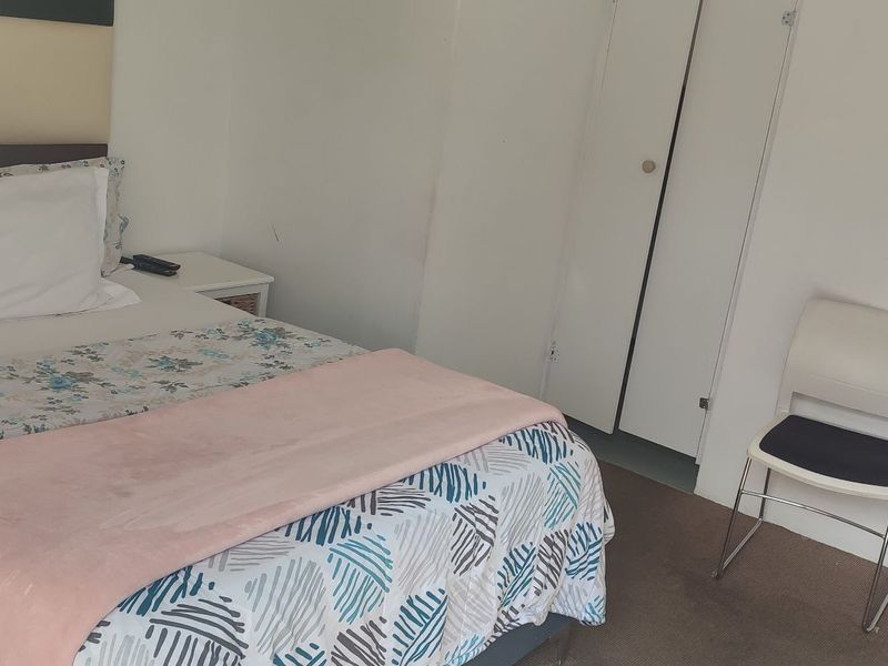 A functional bedroom featuring neutral walls, carpeted flooring, and a built-in wardrobe, offering a simple and practical living space.