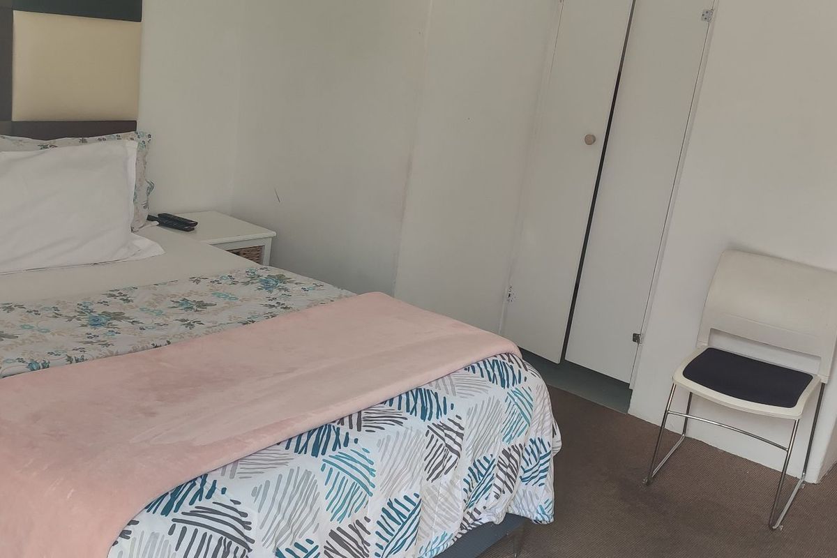 A functional bedroom featuring neutral walls, carpeted flooring, and a built-in wardrobe, offering a simple and practical living space.