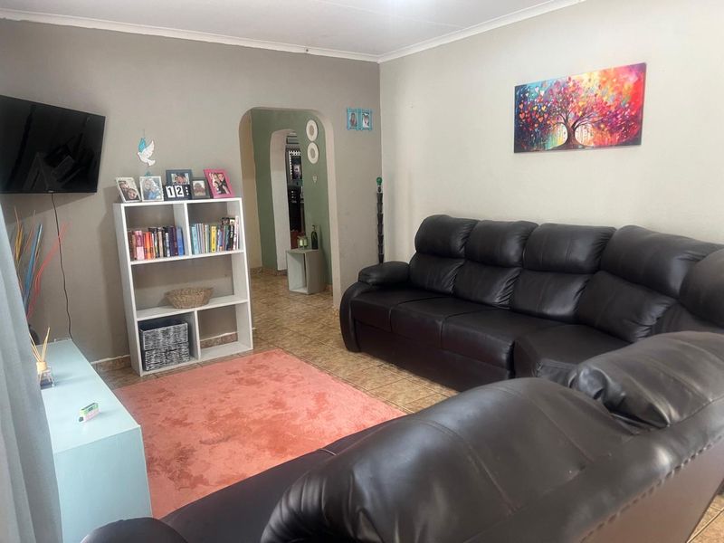 A living room featuring tiled flooring and an arched doorway leading to an adjacent space.
