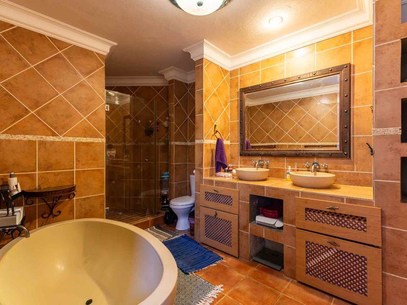 Spacious bathroom featuring a double vanity with vessel sinks, a freestanding bathtub, a walk-in shower, and warm-toned tiled finishes throughout.