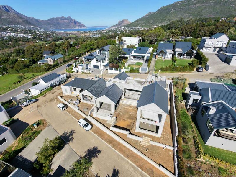 Aerial view of a residential property under construction, featuring a modern pitched roof design and surrounding neighborhood landscape.