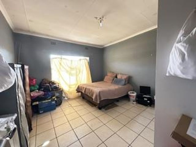 A bedroom featuring tiled flooring and ceiling cornicing, currently requiring maintenance to the ceiling panels.