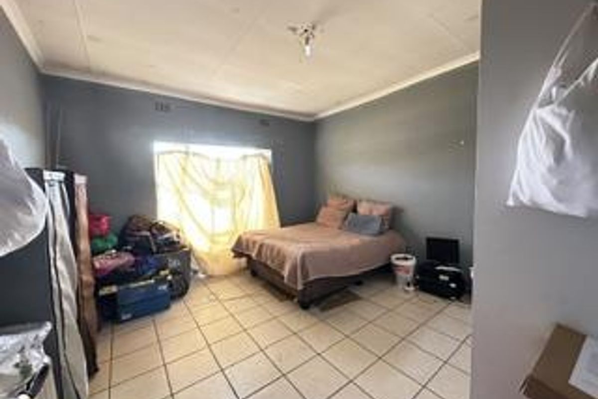 A bedroom featuring tiled flooring and ceiling cornicing, currently requiring maintenance to the ceiling panels.
