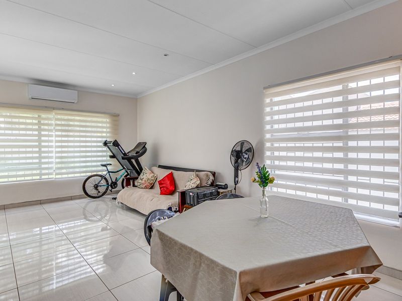 A bright, open-plan living area featuring polished floor tiles, recessed downlighting, and a wall-mounted air conditioning unit.