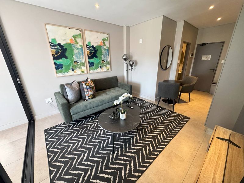 A modern, well-maintained living room featuring neutral walls, tiled flooring, recessed lighting, and a large sliding glass door providing natural light.