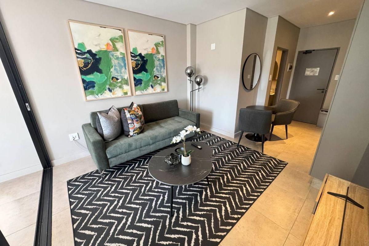 A modern, well-maintained living room featuring neutral walls, tiled flooring, recessed lighting, and a large sliding glass door providing natural light.