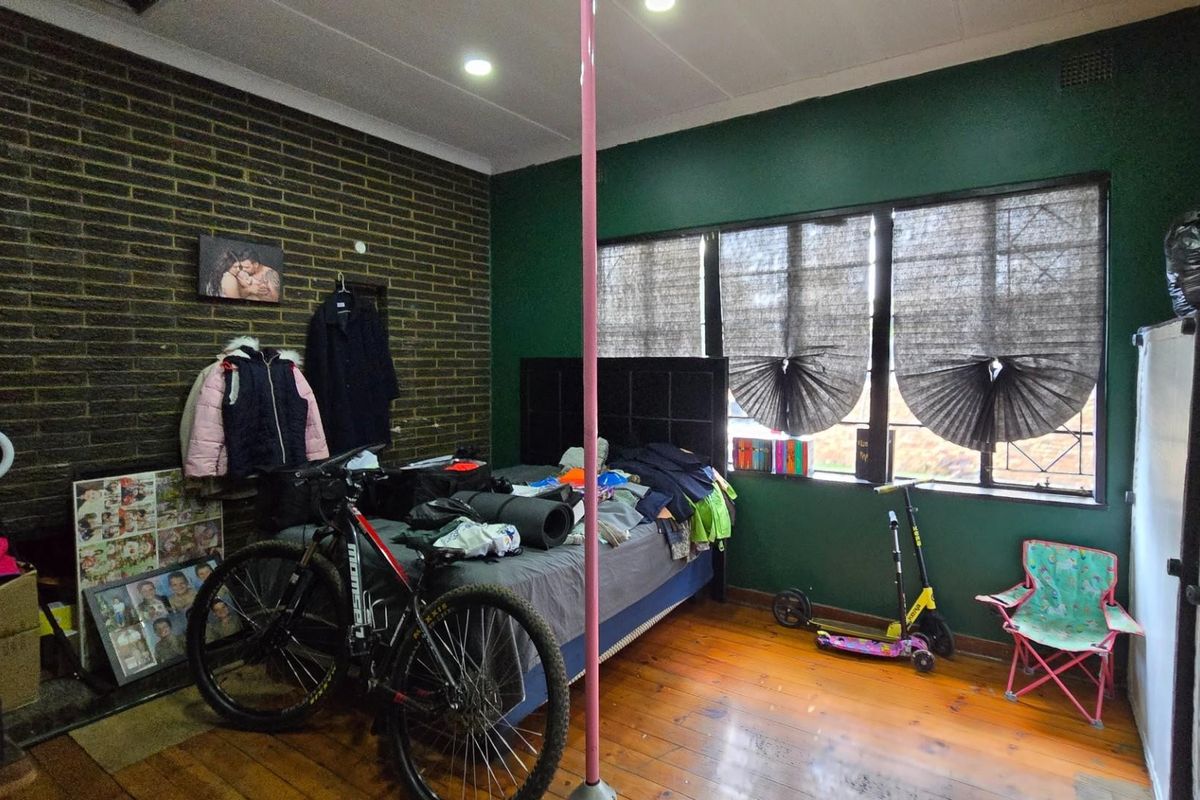 A bedroom featuring exposed brickwork, hardwood flooring, and recessed lighting, offering a unique industrial aesthetic with potential for modern updates.