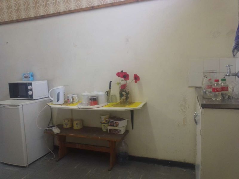A basic kitchen area featuring a sink, tiled splashback, and base cabinetry, showing signs of wear and wall surface deterioration.