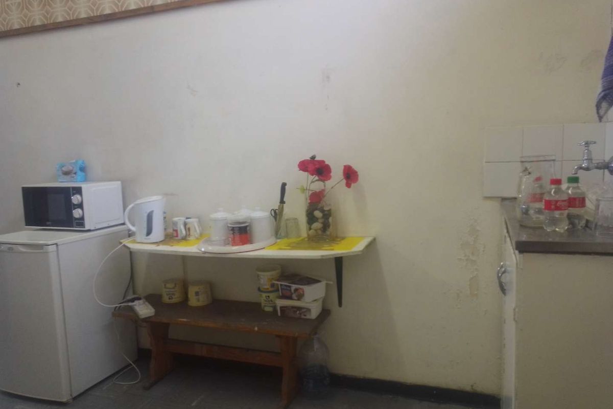 A basic kitchen area featuring a sink, tiled splashback, and base cabinetry, showing signs of wear and wall surface deterioration.