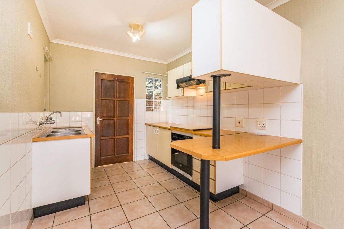 A functional kitchen featuring built-in cabinetry, laminate countertops, a breakfast bar, and integrated oven with extractor fan, finished with ceramic tile flooring.