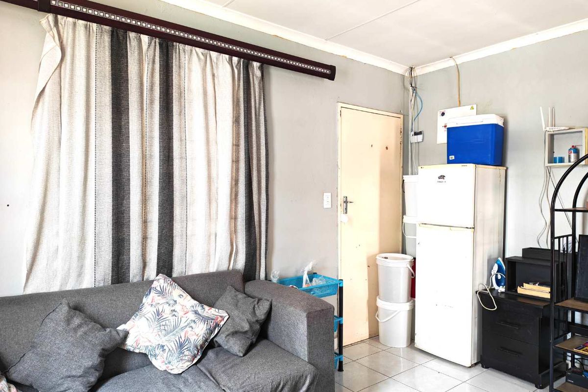 A living area featuring tiled flooring, a standard interior door, and exposed wall-mounted electrical cabling.