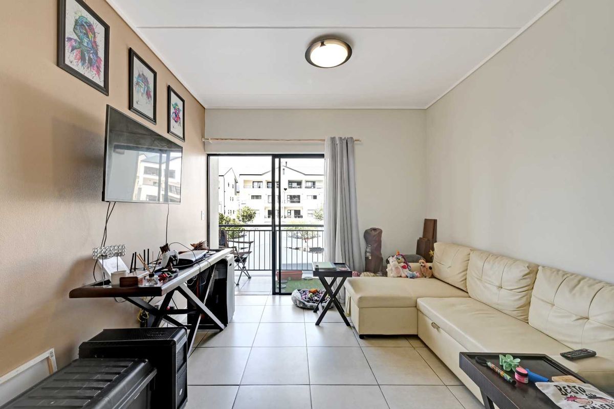 A living room featuring tiled flooring and a sliding glass door that opens onto a private balcony.