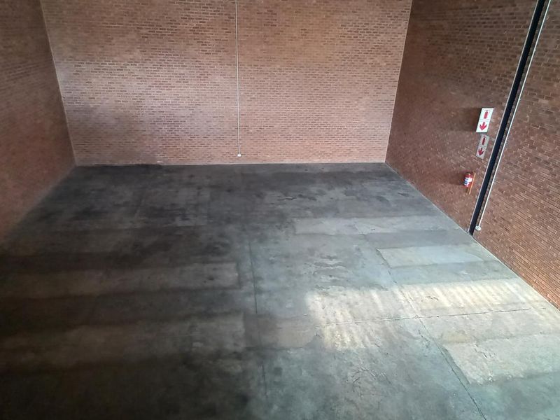 Spacious industrial utility area featuring exposed brick walls and durable concrete flooring, equipped with essential fire safety equipment.