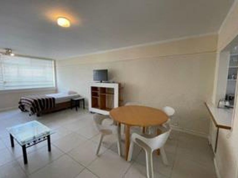 Open-plan living and dining area featuring tiled flooring, neutral walls, and a convenient pass-through window connecting to the kitchen space.