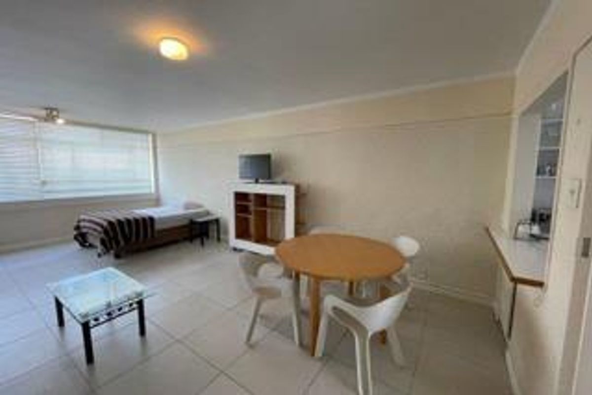Open-plan living and dining area featuring tiled flooring, neutral walls, and a convenient pass-through window connecting to the kitchen space.