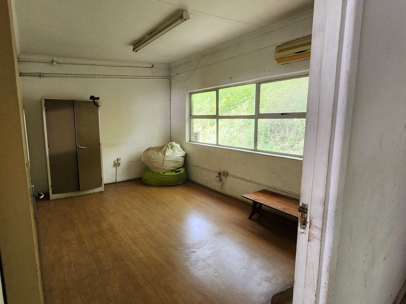 A functional office space featuring laminate flooring, large windows for natural light, and a wall-mounted air conditioning unit.