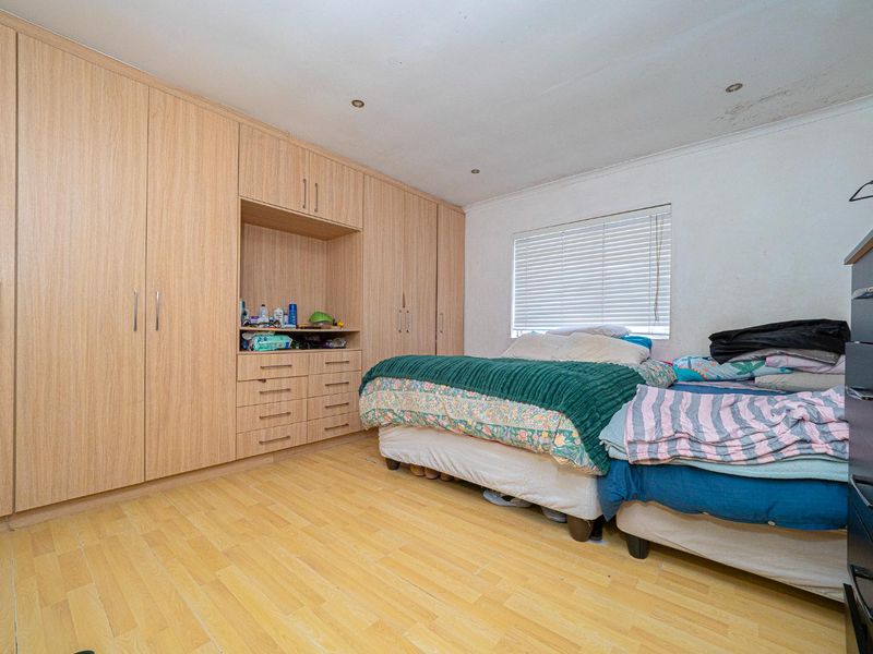 A bedroom featuring extensive built-in wooden cabinetry, laminate flooring, and recessed lighting, with visible signs of ceiling water damage requiring attention.