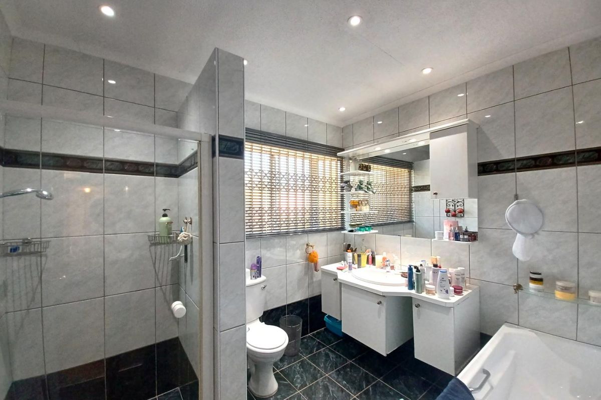 A functional bathroom featuring a walk-in shower, a built-in vanity with integrated basin, a toilet, and a bathtub with tiled walls and flooring.