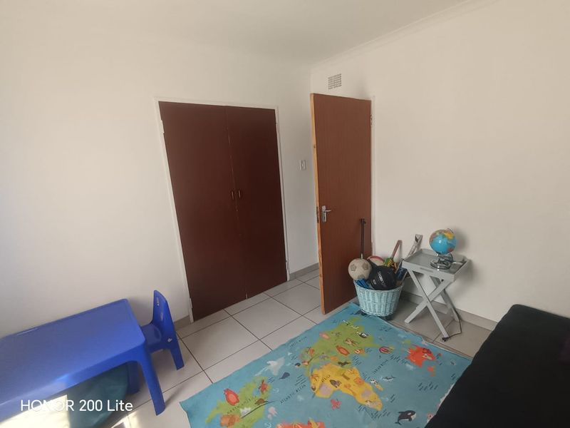 A simple bedroom featuring tiled flooring and built-in cupboards, providing a functional space ready for personalization.
