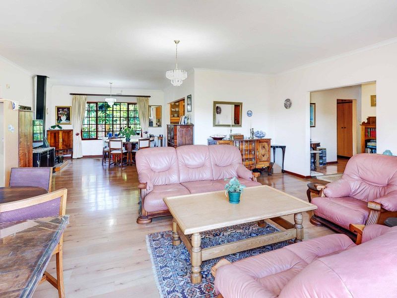 Spacious open-plan living and dining area featuring hardwood flooring, a fireplace, and large windows providing ample natural light.