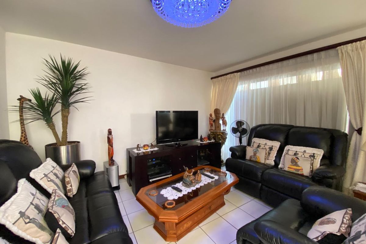 A comfortable living room featuring tiled flooring and a decorative crystal chandelier, providing a functional space for relaxation.
