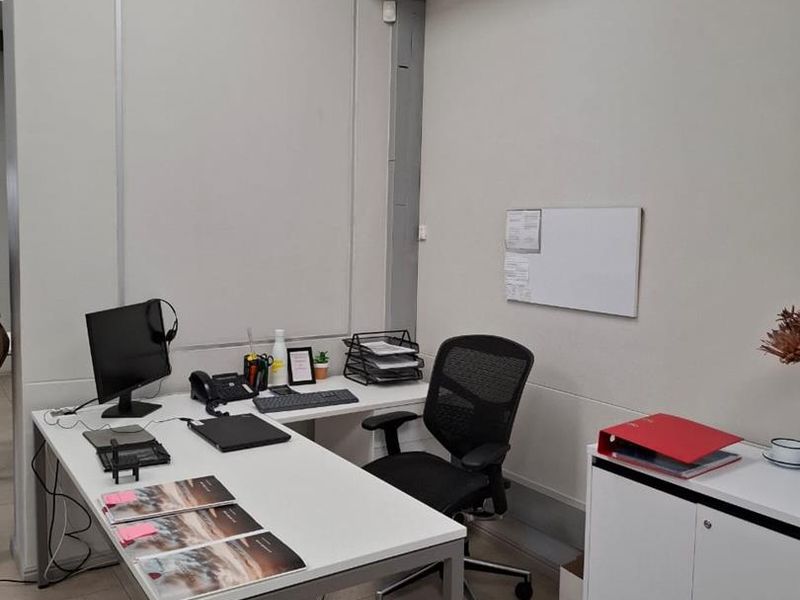 A functional office space featuring tiled flooring, recessed ceiling lighting, and wall-mounted whiteboard, providing a clean and professional work environment.