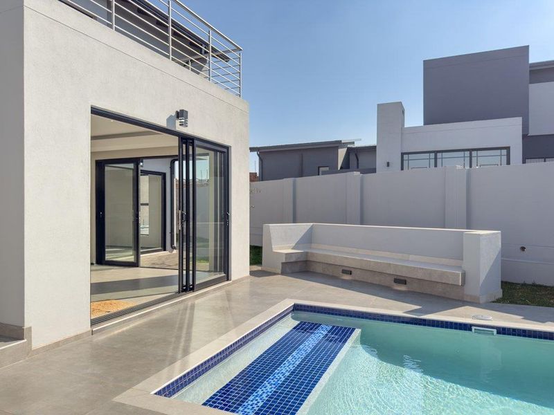 Modern outdoor pool area featuring a tiled patio, built-in bench seating, and seamless access to the interior through large sliding glass doors.
