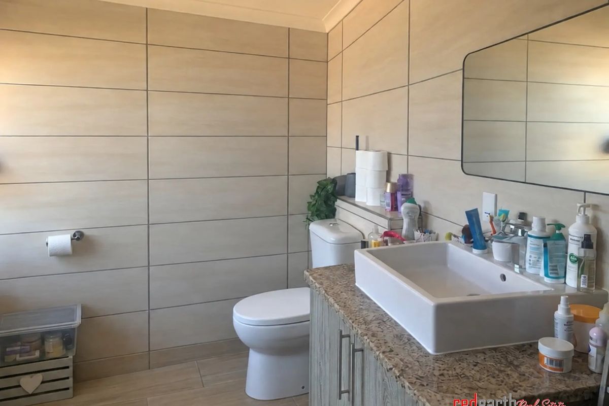 A modern bathroom featuring tiled walls, a granite-topped vanity with a vessel sink, and a wall-mounted toilet.