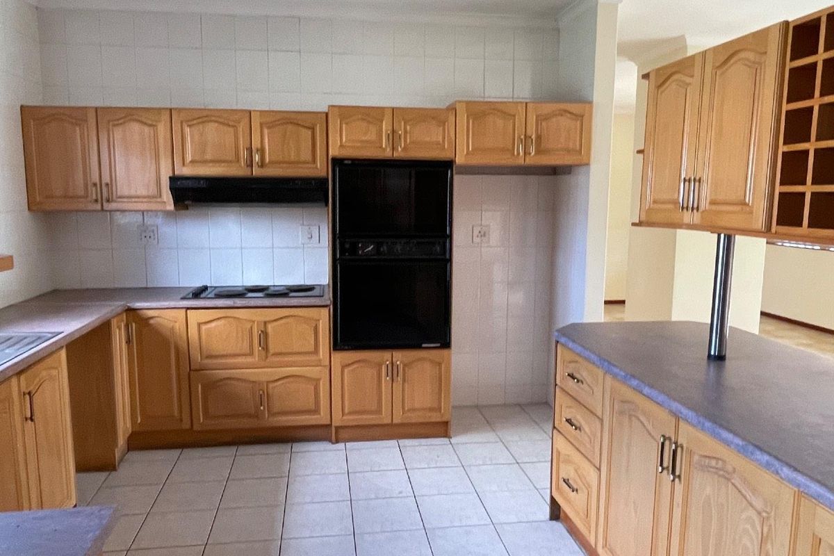 A functional kitchen featuring traditional wooden cabinetry, built-in oven, electric hob, and tiled finishes, offering a blank canvas for modern renovation.