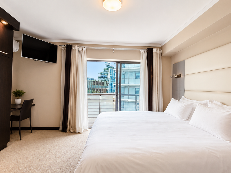 A well-maintained bedroom featuring a large built-in wardrobe, a modern upholstered headboard, and a sliding door leading to a private balcony.