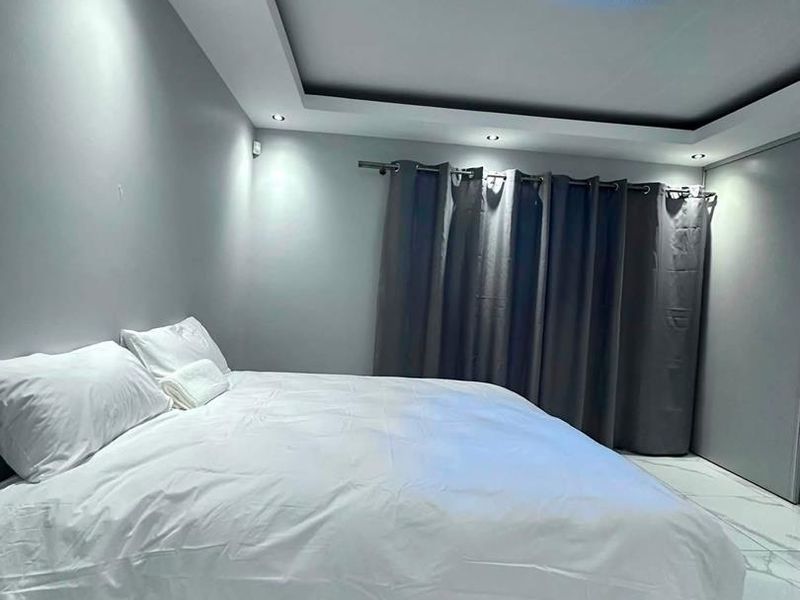 A modern bedroom featuring marble-look floor tiles, recessed ceiling lighting, and built-in wardrobe storage.