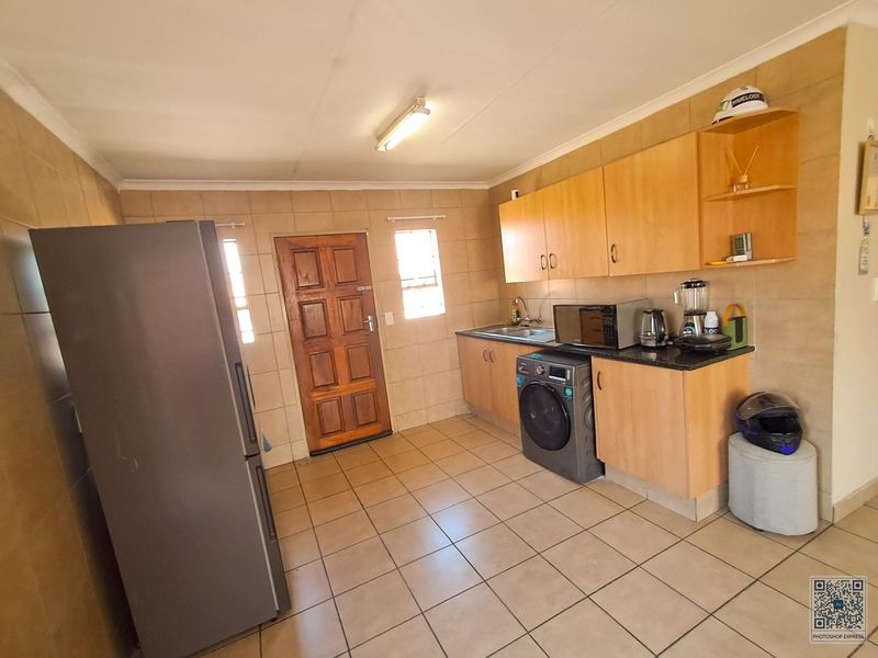 A functional kitchen featuring built-in wooden cabinetry, granite countertops, tiled walls, and tiled flooring, providing a practical workspace with direct exterior access.