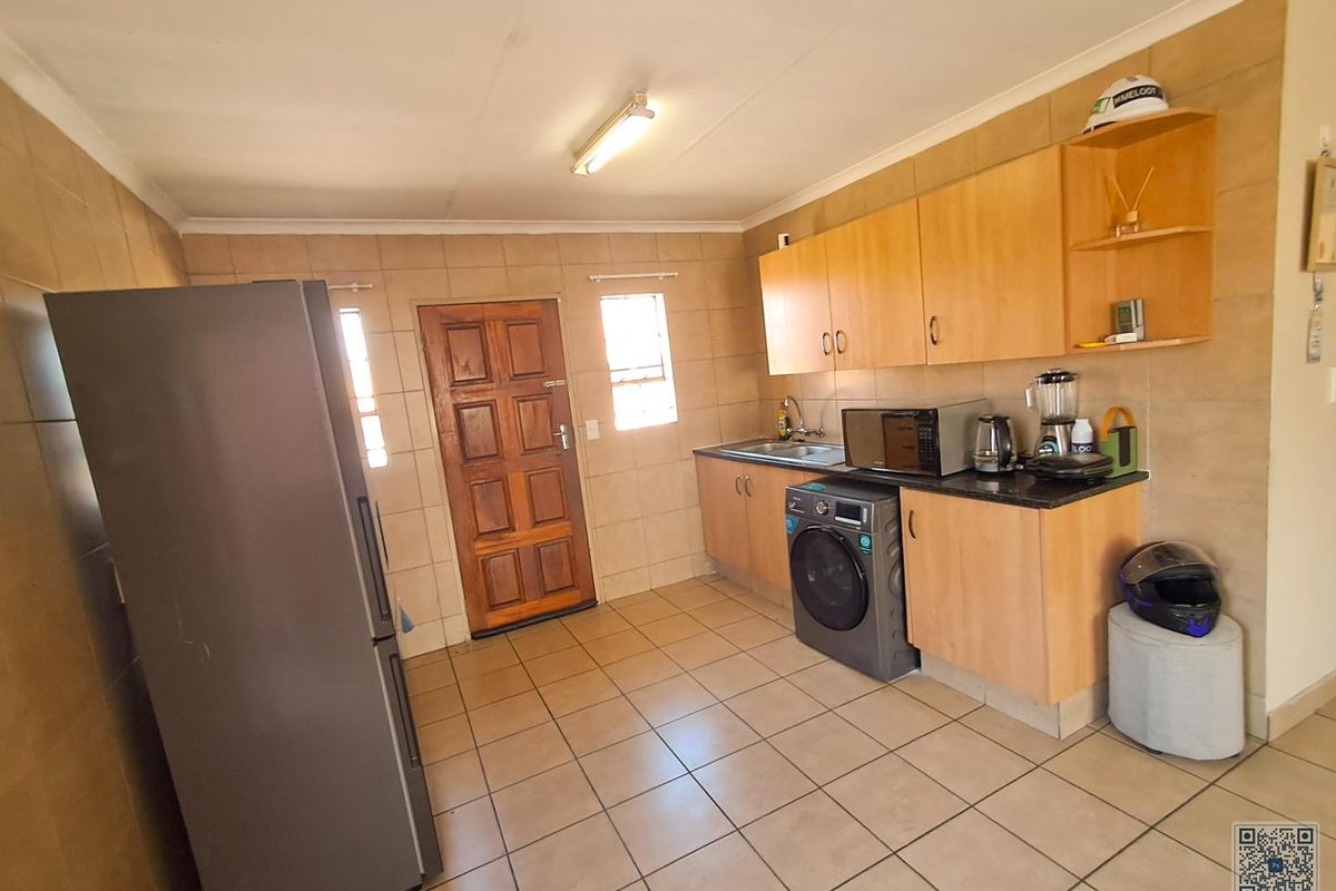 A functional kitchen featuring built-in wooden cabinetry, granite countertops, tiled walls, and tiled flooring, providing a practical workspace with direct exterior access.
