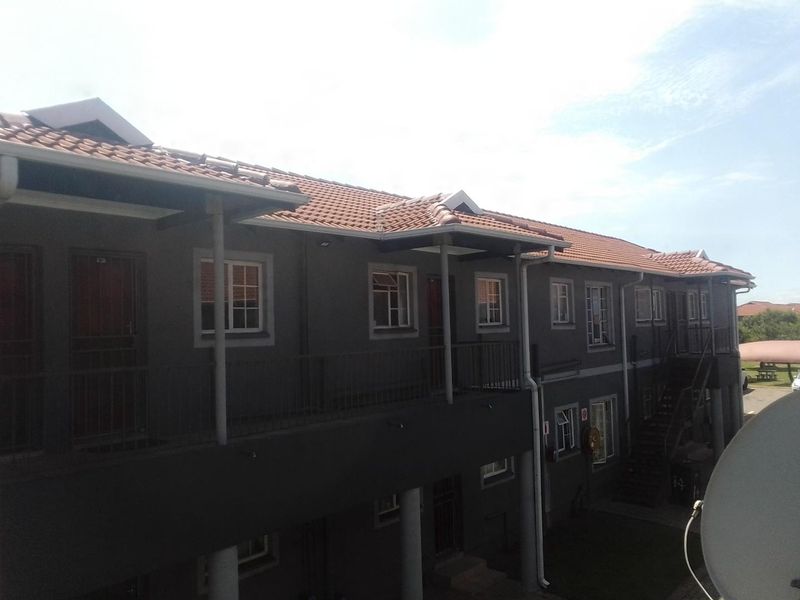 Exterior view of a multi-story apartment complex featuring tiled roofing, metal balcony railings, and external stair access.