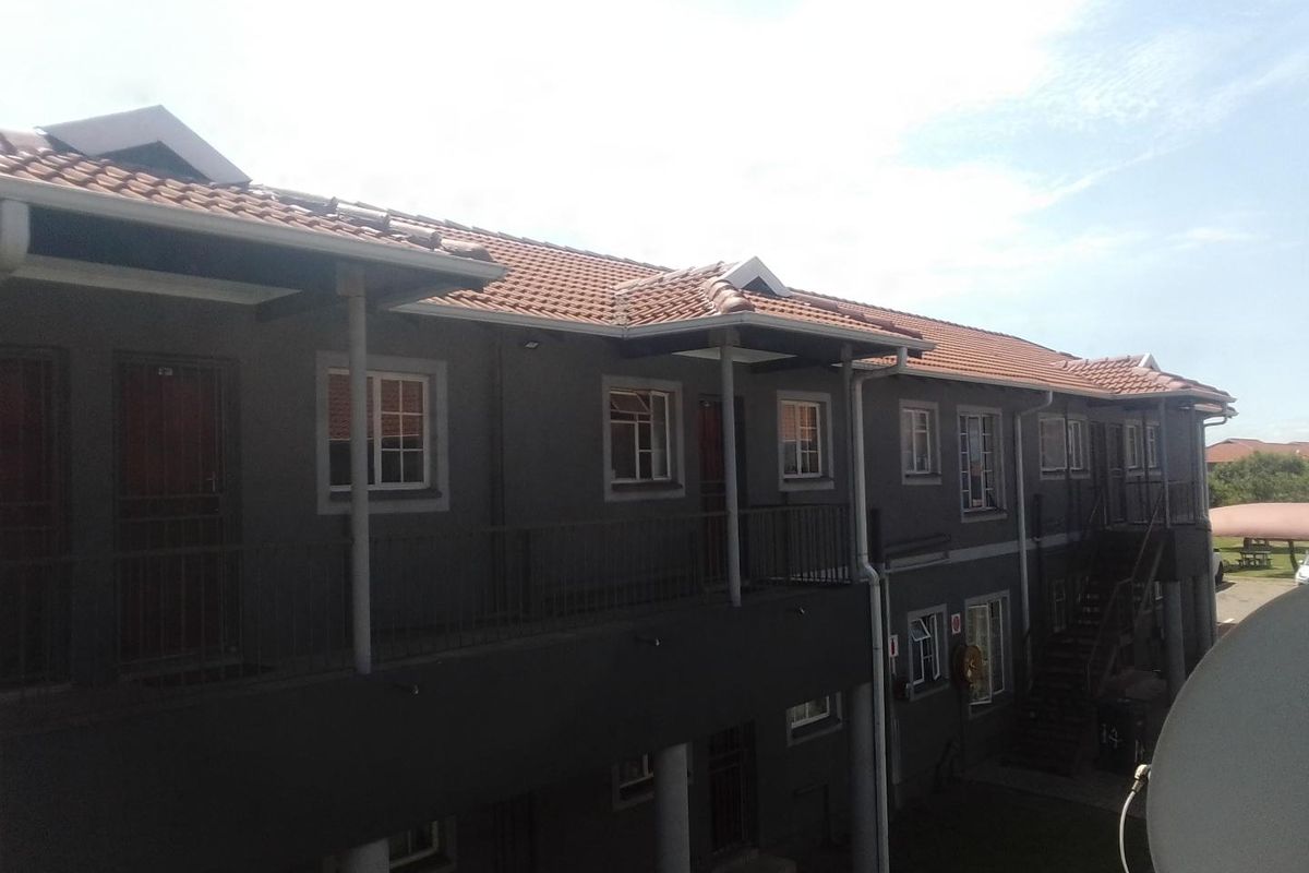 Exterior view of a multi-story apartment complex featuring tiled roofing, metal balcony railings, and external stair access.