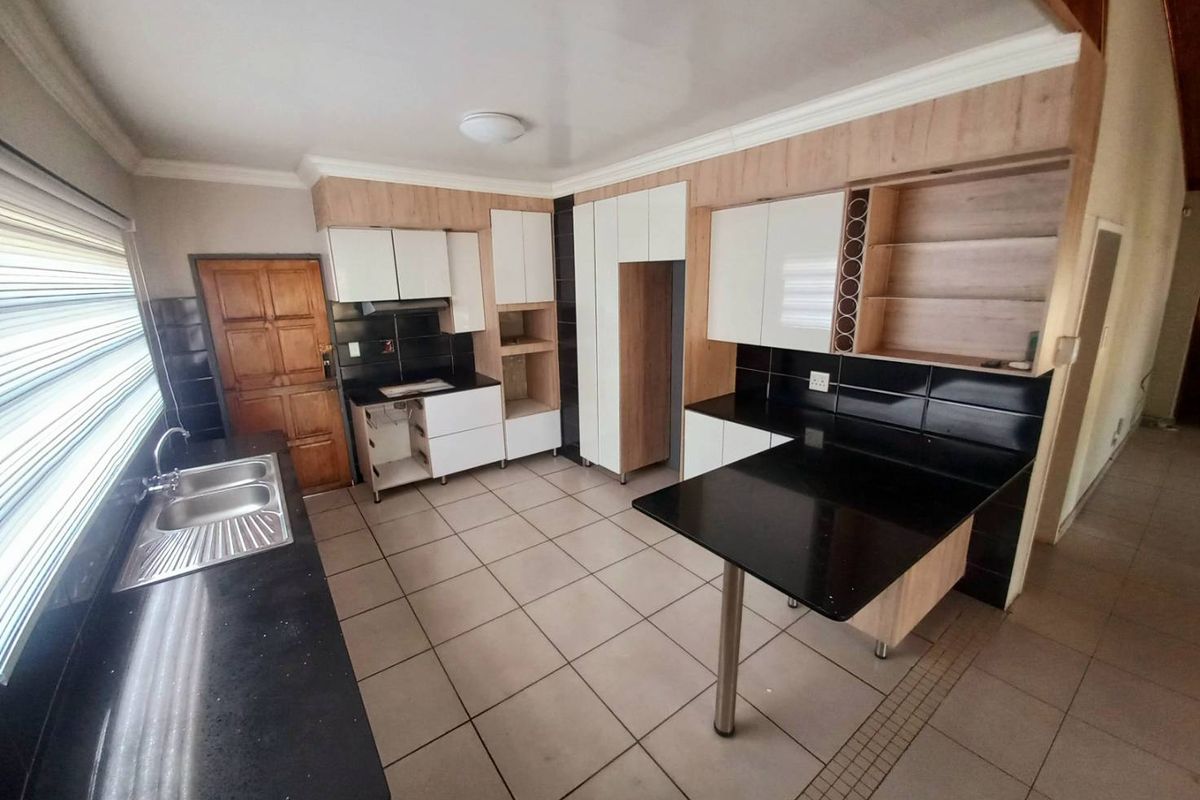 A functional kitchen featuring black granite countertops, two-tone cabinetry, tiled flooring, and a breakfast bar extension.