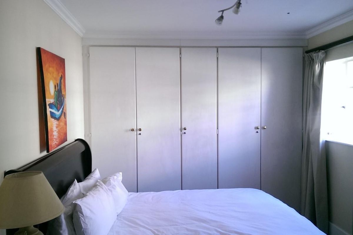 A bedroom featuring floor-to-ceiling built-in cupboards, decorative ceiling coving, and adjustable track lighting, providing ample storage and functional illumination.