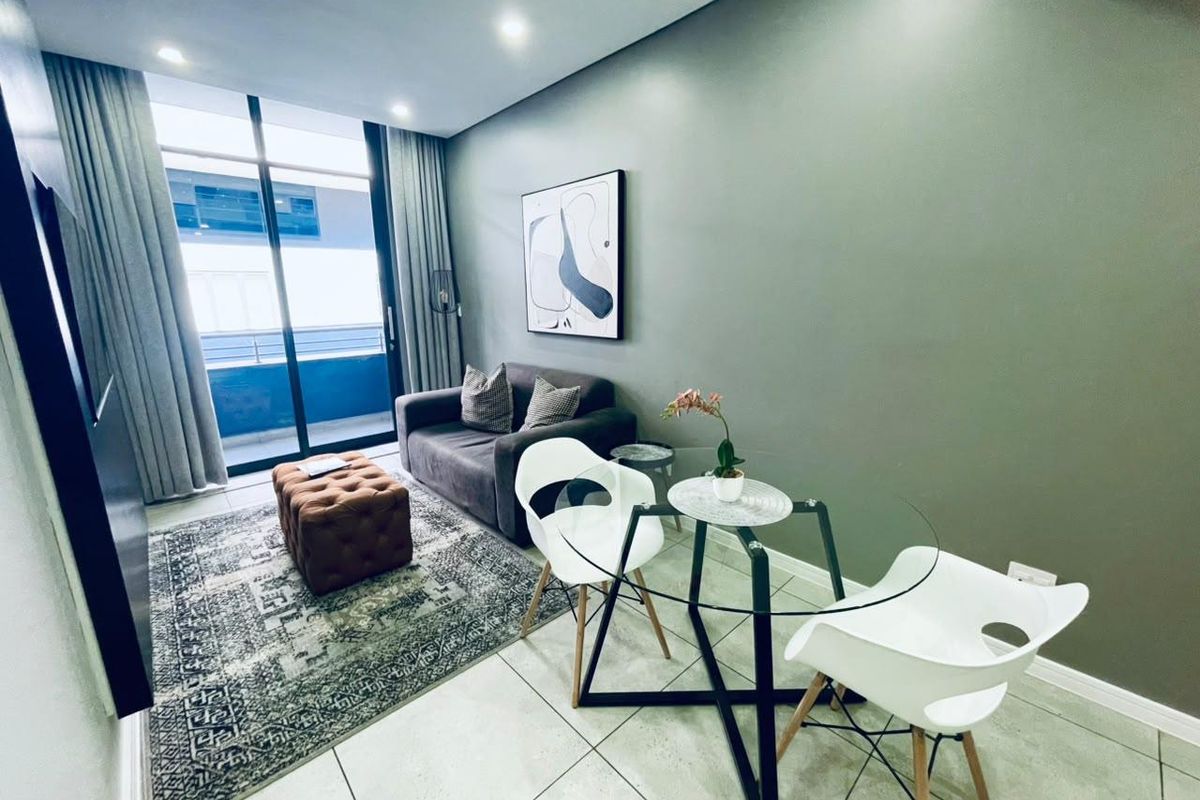 A modern living area featuring tiled flooring, recessed downlighting, and a large sliding glass door providing access to the balcony.