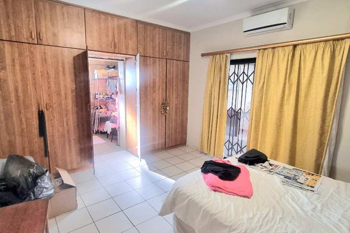 A bedroom featuring extensive built-in wooden cabinetry, tiled flooring, and a wall-mounted air conditioning unit.