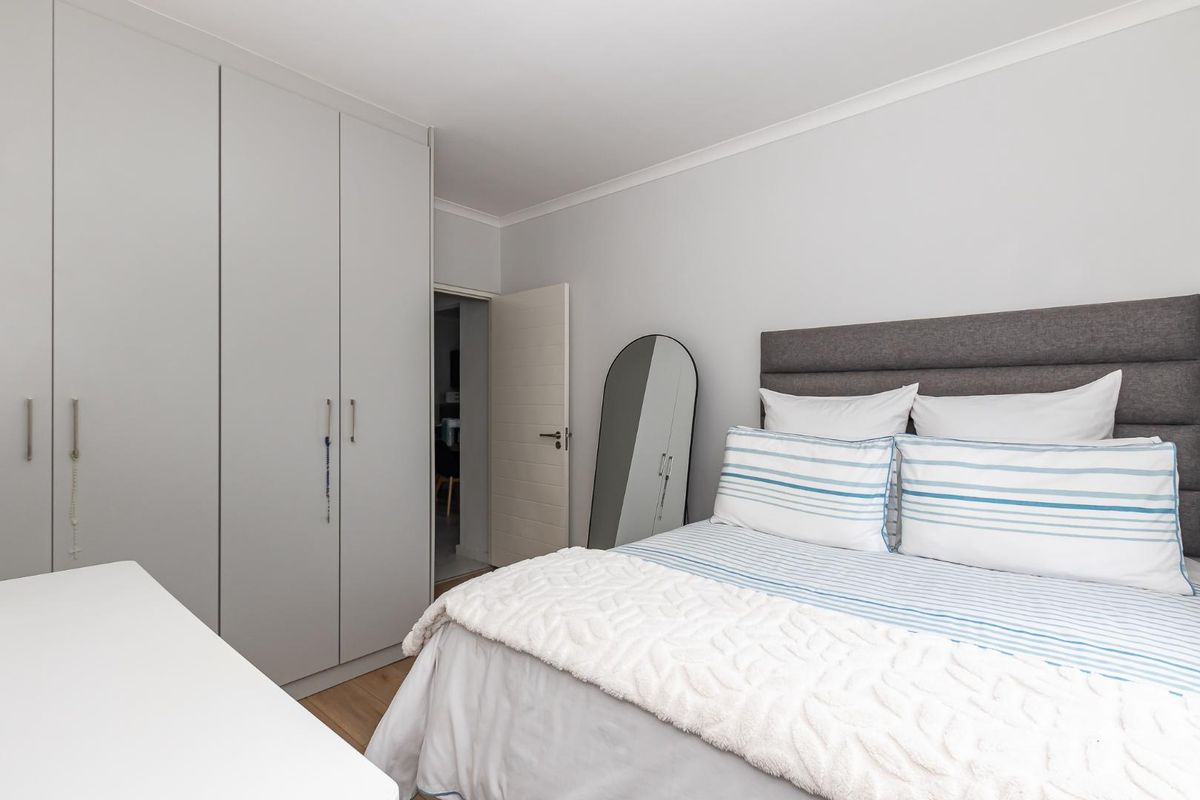 A well-maintained bedroom featuring built-in floor-to-ceiling wardrobes and neutral finishes, providing a clean and functional living space.