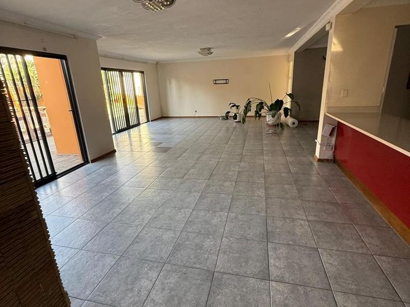 Spacious open-plan living area featuring large format floor tiles, coved ceilings, and sliding glass doors providing access to the outdoor patio area.