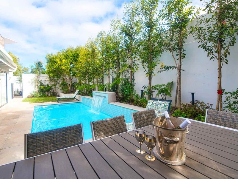 A well-maintained outdoor pool area featuring a modern water feature, tiled surround, and landscaped garden borders, perfect for relaxation and outdoor entertaining.