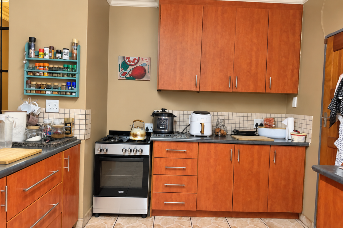 A functional kitchen featuring warm-toned wooden cabinetry, tiled backsplash, and a freestanding oven, offering a practical layout with ample storage space.